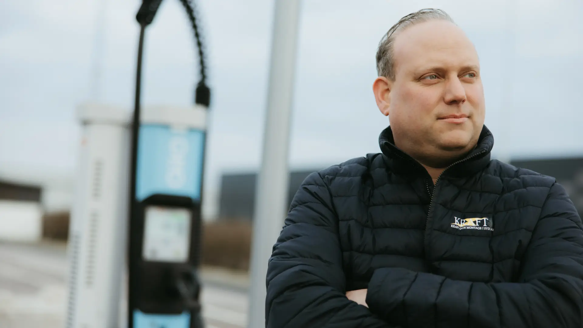 The owner of Kraft & Montage i Syd standing in front of an electric charger
