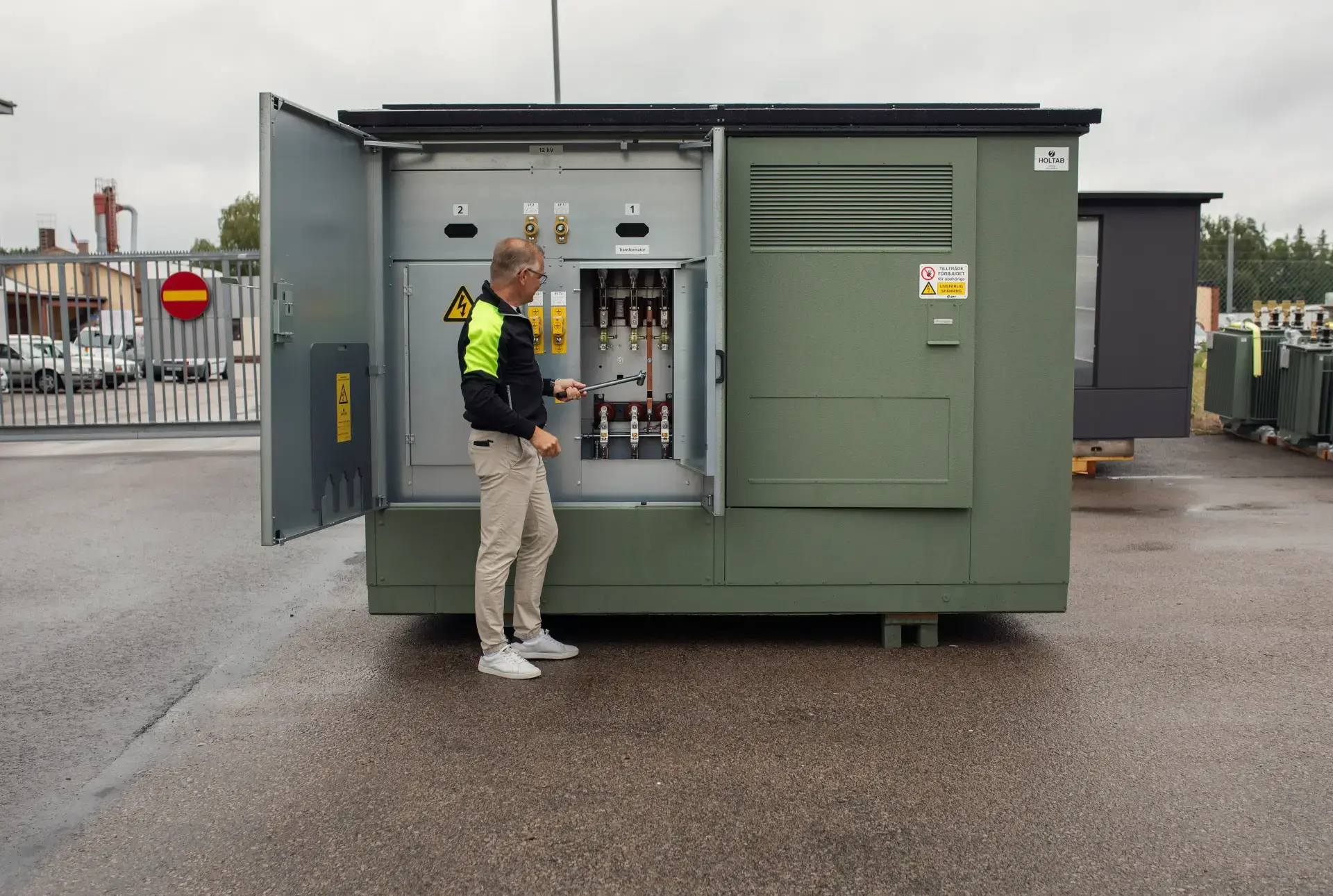 A Holtab employee standing in front of a secondary substation
